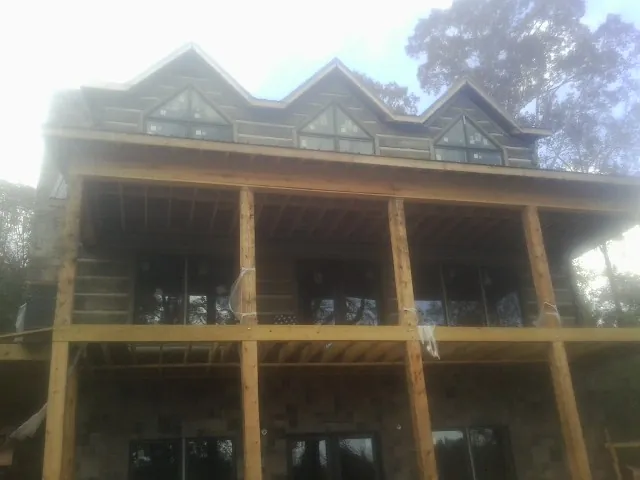 Dormers and porch framing on a large log home under construction — Roof Coating work by our crew in Littlerock