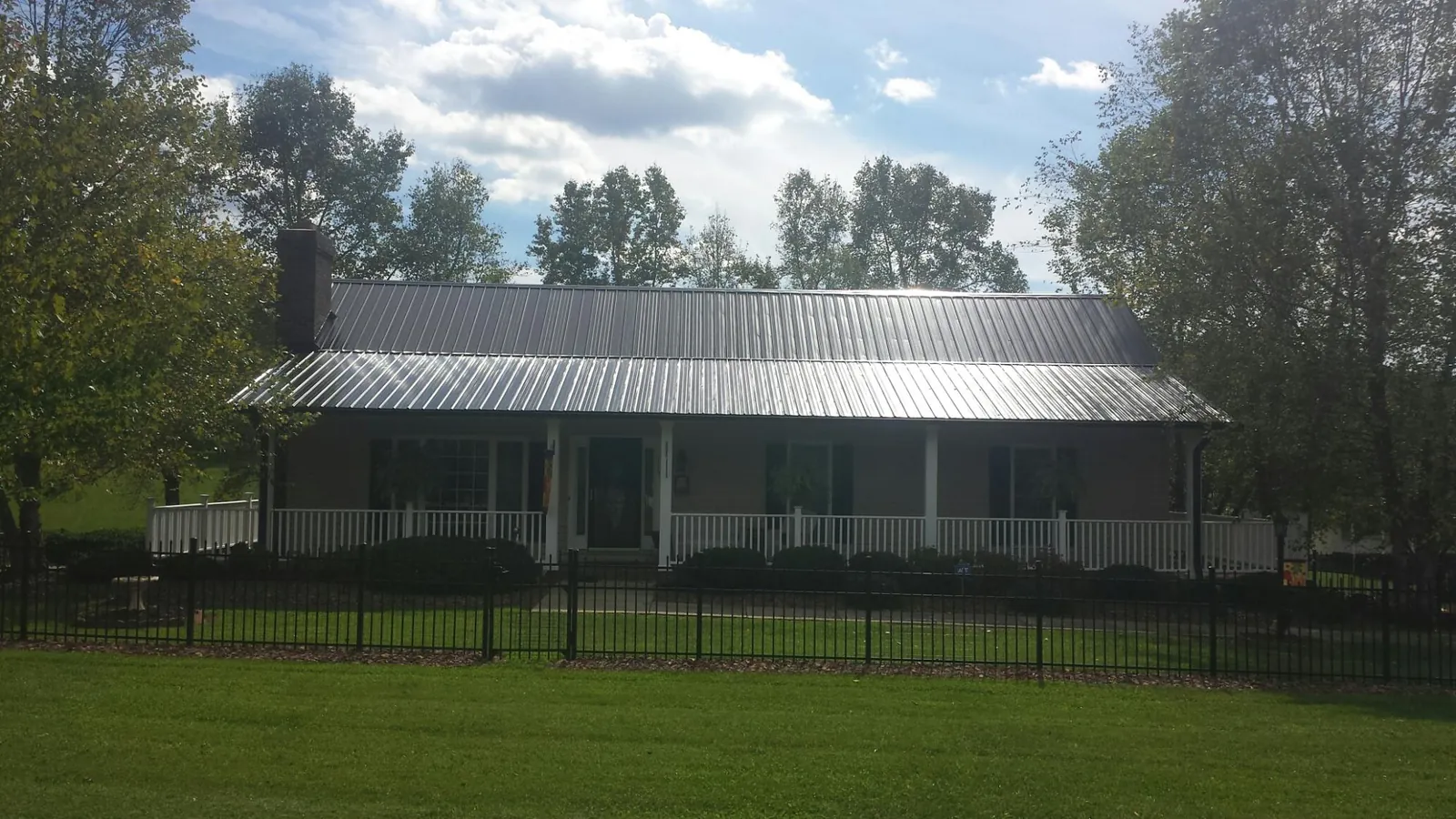Gray metal roof on a brick ranch with a full width front porch — Gutter Guard Installation work by our crew in Littlerock