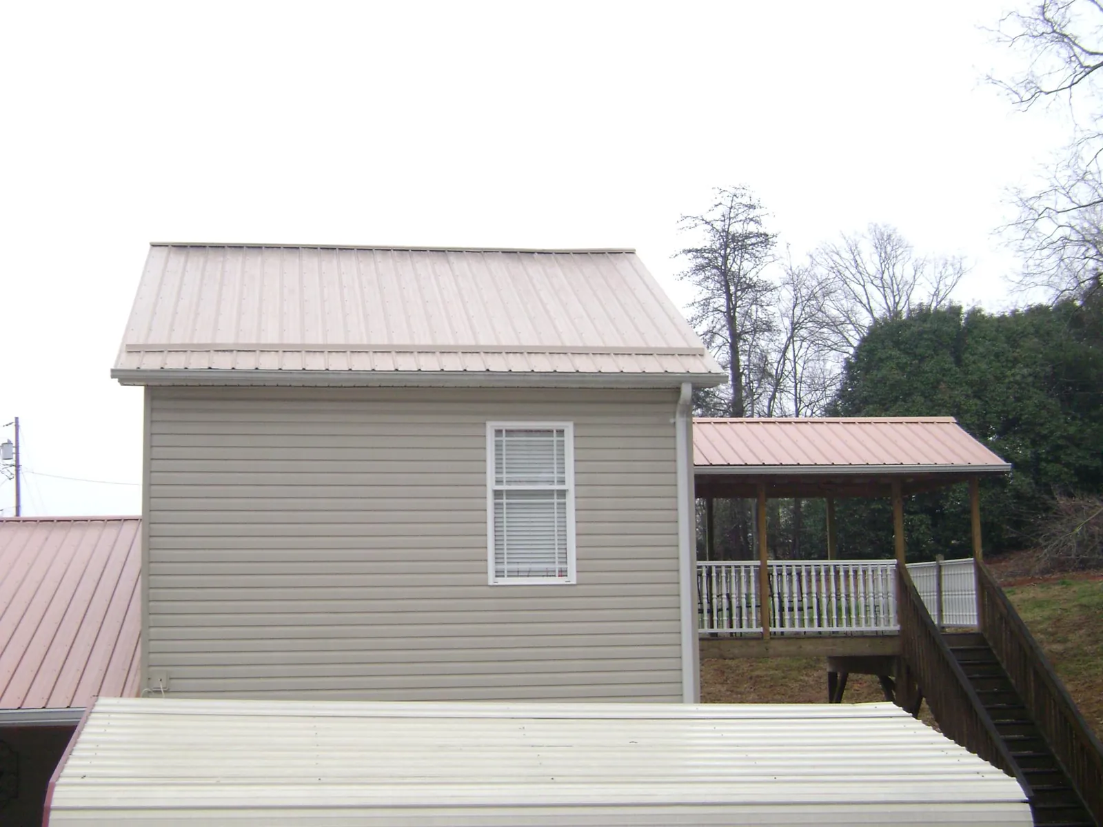 Tan metal roofs on a two story addition and attached porch, from a Roof Replacement job in Littlerock