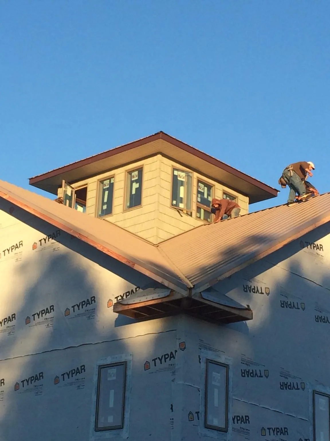 Roofers working around a rooftop cupola on a new metal roof at sunset — Roof Waterproofing in Littlerock by Roofing Brothers